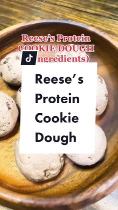 a wooden bowl filled with cookies on top of a table next to a sign that says reese's protein cookie dough ingredients