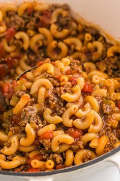 a large pot filled with pasta and ground beef in it's sauce being stirred by a ladle