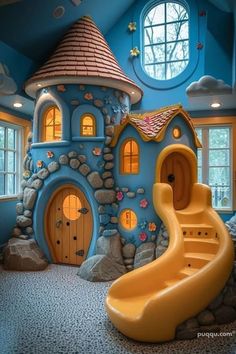 a blue and yellow house with a slide next to it in the middle of a room