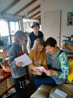 a group of people standing around each other in a living room looking at a piece of paper