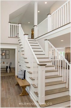 there is a white staircase in the middle of this house with wood flooring and wooden handrails