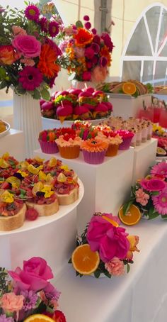 a table topped with lots of different types of food on top of white pedestals