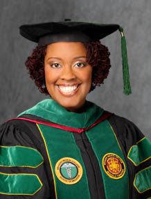 a woman wearing a green and black graduation gown