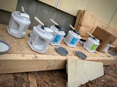 several paint cans are lined up on a pallet and some tools are laying next to them