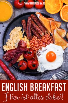 a black plate topped with eggs, bacon, beans and toast next to oranges