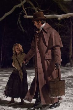 a man and woman are walking in the snow holding hands with each other as they hold suitcases