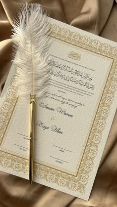 a feather quill resting on top of a marriage certificate next to a golden pen