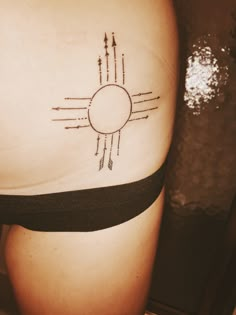 a woman's thigh with an arrow and sun tattoo on her lower back side