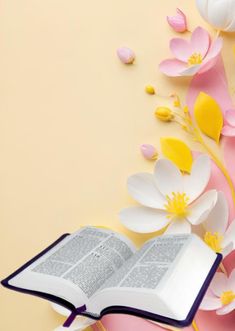 an open book sitting on top of a table with paper flowers and petals around it