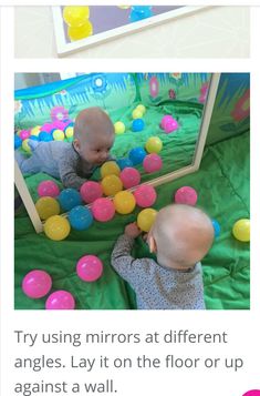 two babies playing with balls in front of a mirror