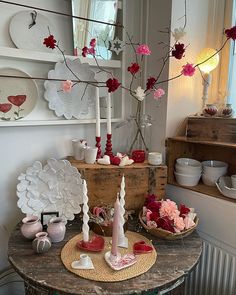 a table topped with plates and vases next to a tree filled with pink flowers