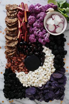 an assortment of different foods on a white marble counter top, including cauliflower, blackberries, and other veggies