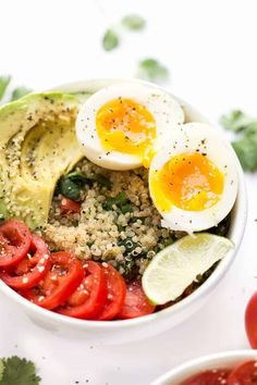 a bowl filled with eggs, tomatoes and quinoa on top of a table