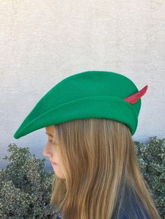 a woman with long blonde hair wearing a green beret and red arrow on it