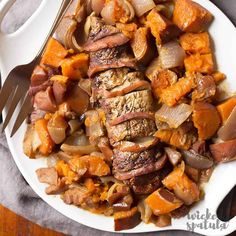 a white plate topped with meat and veggies next to a knife and fork