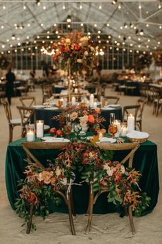 a table with candles, flowers and greenery is set up for an outdoor reception