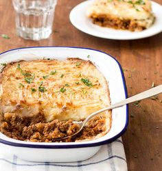 a casserole dish with meat and cheese in it sitting on a wooden table