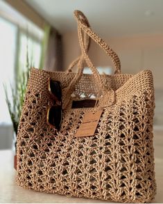 a crocheted handbag sitting on top of a table next to a potted plant