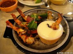 a plate full of food with shrimp and dipping sauce on the side at a restaurant