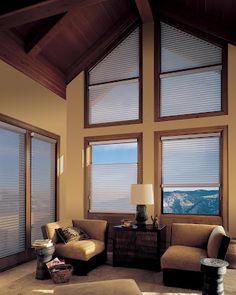 a living room filled with furniture and large windows covered in shades of blue, white and brown