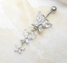 "14g surgical steel belly bar with sparkly cubic zirconia butterfly duo and dainty flower charm. Belly ring measures 1 3/4 inches long total length. Barbell is 14g surgical steel with 7/16\" (11mm) wearable bar length. For Belly Button Rings: https://www.etsy.com/shop/AllAboutClass?section_id=18474235&ref=shopsection_leftnav_1 All body jewelry sales are final!! AllAboutClass DOES NOT accept any returns on body jewelry for sanitary reasons. This is a standard policy in the body jewelry industry t Wedding Jewelry With Butterfly Charm In Cubic Zirconia, Wedding Jewelry With Cubic Zirconia Butterfly Charm, Silver Cubic Zirconia Belly Rings For Wedding, Dainty Silver Belly Rings For Wedding, Dream Piercings, Butterfly Sparkle, Bellybutton Piercings, Belly Piercing Jewelry, Belly Bar