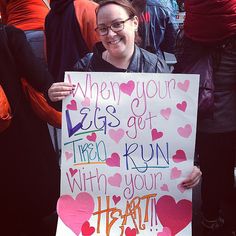 a woman holding a sign that says when your legs get tired, try to run with your heart