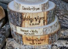 three wooden slices with names on them stacked up next to each other in front of wood logs