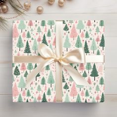 a present wrapped in white paper with a bow on top of it next to christmas decorations