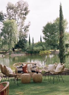 wicker furniture is arranged on the grass near a pond