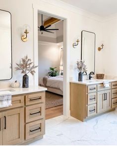 a bathroom with two sinks and mirrors in it's center area, along with a bed