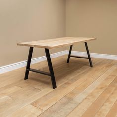 a wooden table sitting on top of a hard wood floor next to a white wall