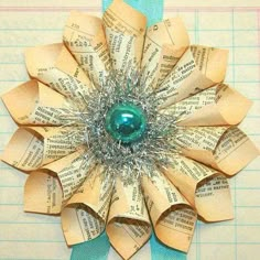 an origami flower made out of old book pages is displayed on a piece of paper