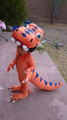 a small child in an orange dinosaur costume