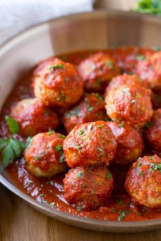 some meatballs are covered in sauce and garnished with parsley