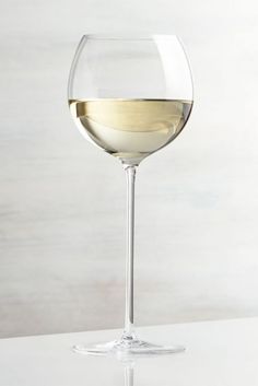 a glass of white wine sitting on top of a table