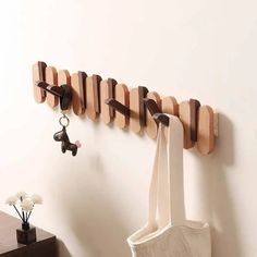 a wooden coat rack with hooks on it and a tote bag hanging from the wall