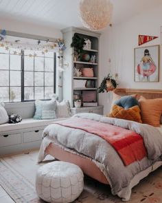 a bed room with a neatly made bed next to a window and a bench in front of it