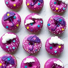 there are many donuts with purple frosting and decorations