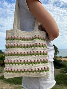 a woman holding a crocheted bag with flowers on it