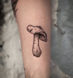 a small mushroom tattoo on the right forearm and leg, it is black and white