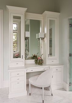 a white dressing table with two chairs and a large mirror on the wall above it