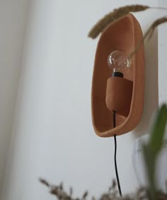 a light that is on the wall next to a potted plant with some plants in it