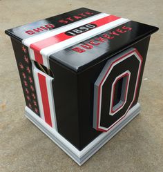 a black and red box with the letter o on it's side sitting on concrete