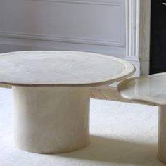 a white marble coffee table sitting on top of a rug next to a vase filled with flowers