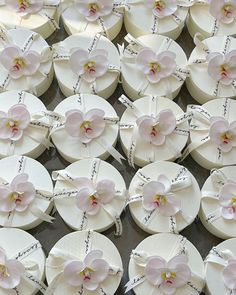 many white and pink flowers are arranged on top of each other with ribbons tied around them