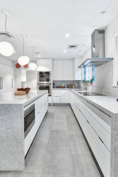 a large kitchen with white cabinets and marble counter tops, along with stainless steel appliances