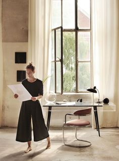 a woman standing in front of a window holding papers