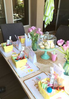 the table is set up with cupcakes and flowers in vases on it