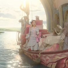 a woman standing on top of a pink boat in the water next to other boats