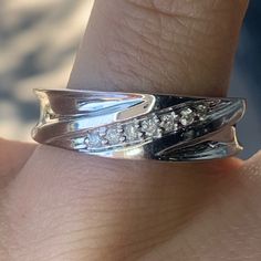 a woman's hand with a silver ring on top of her finger and diamonds in the middle